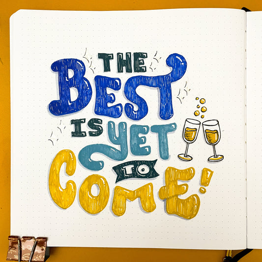 Hand lettered quote for "The Best is Yet to Come" with champagne glass doodles
