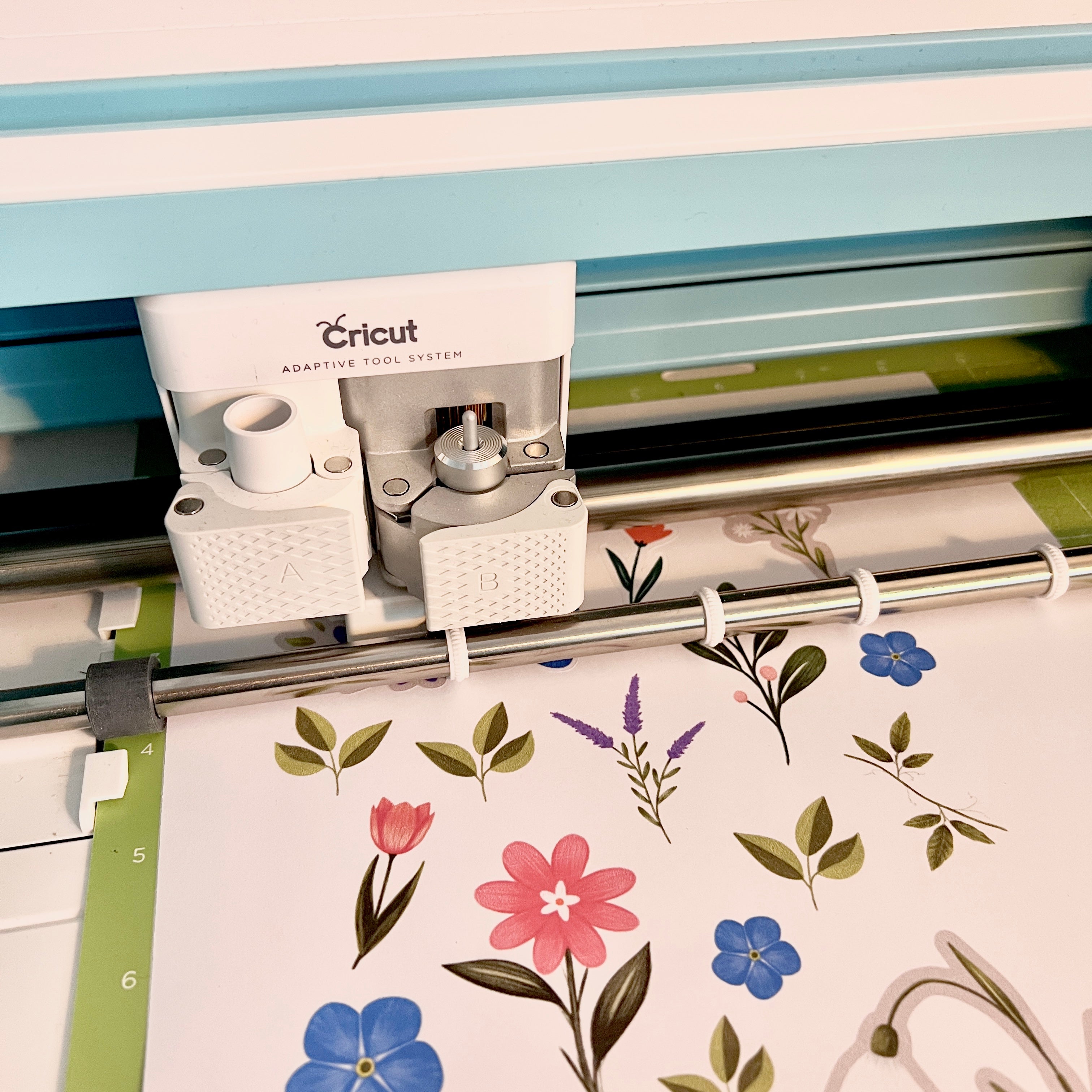Image showing a cutting machine cutting a floral themed sticker sheet featured as a printable in this blog post