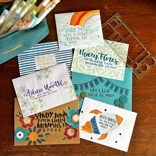 Collection of decorated envelopes along with a stencil and pouch full of markers