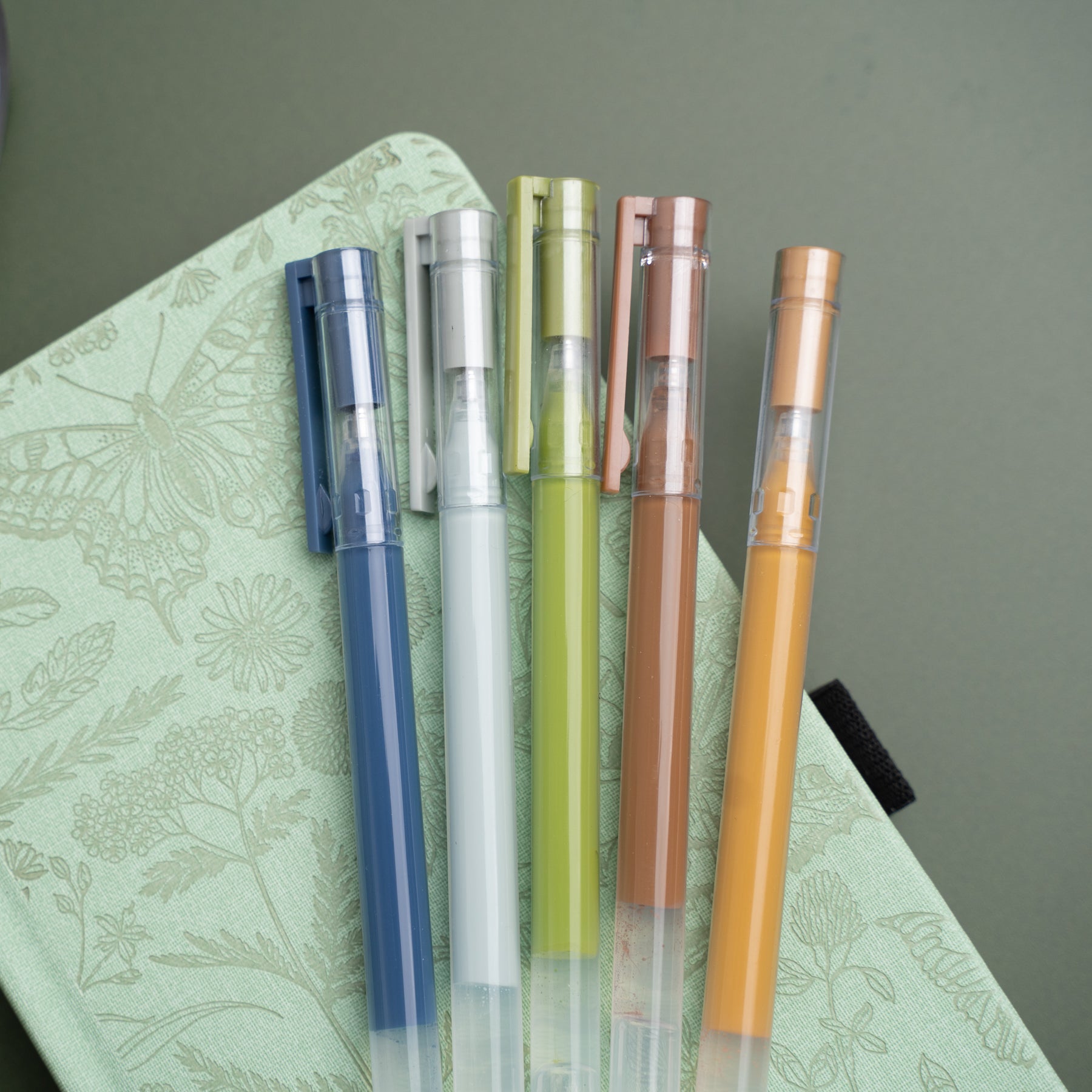 Set of colorful gel pens on a green notebook with butterfly design