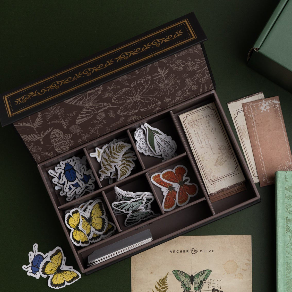 Set of butterfly-themed patches in a decorative box on a dark surface.