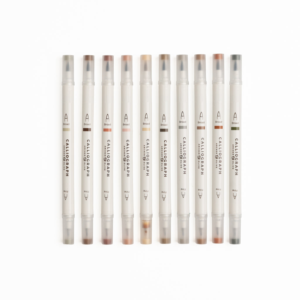 Set of ten Quiet Corners calligraphy pens with flexible brush tips laid out with lettering samples