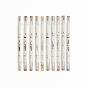 Set of ten Quiet Corners calligraphy pens with flexible brush tips laid out with lettering samples