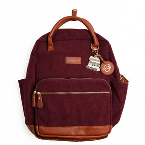 Maroon ribbed corduroy backpack with brown vegan leather trim and book-stack keychain