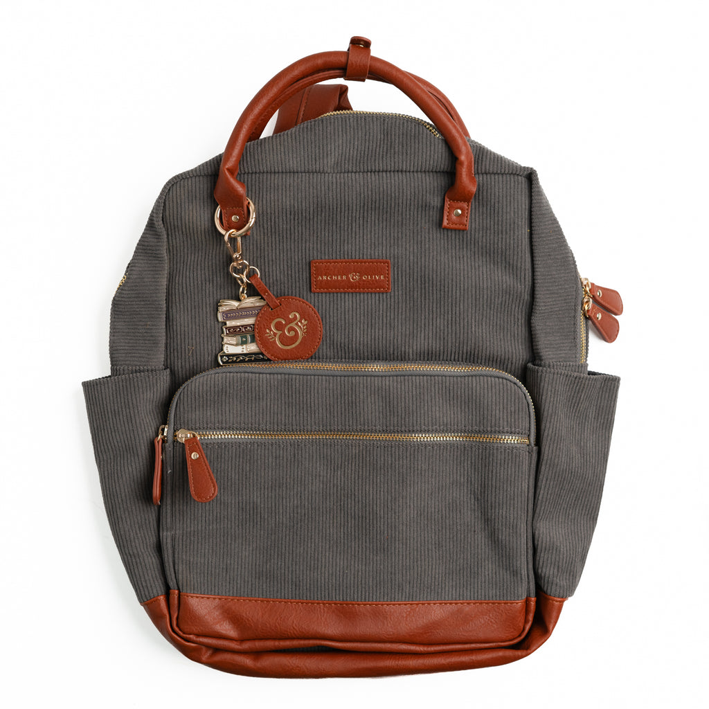 Charcoal gray ribbed corduroy backpack with brown vegan leather trim and book-stack keychain