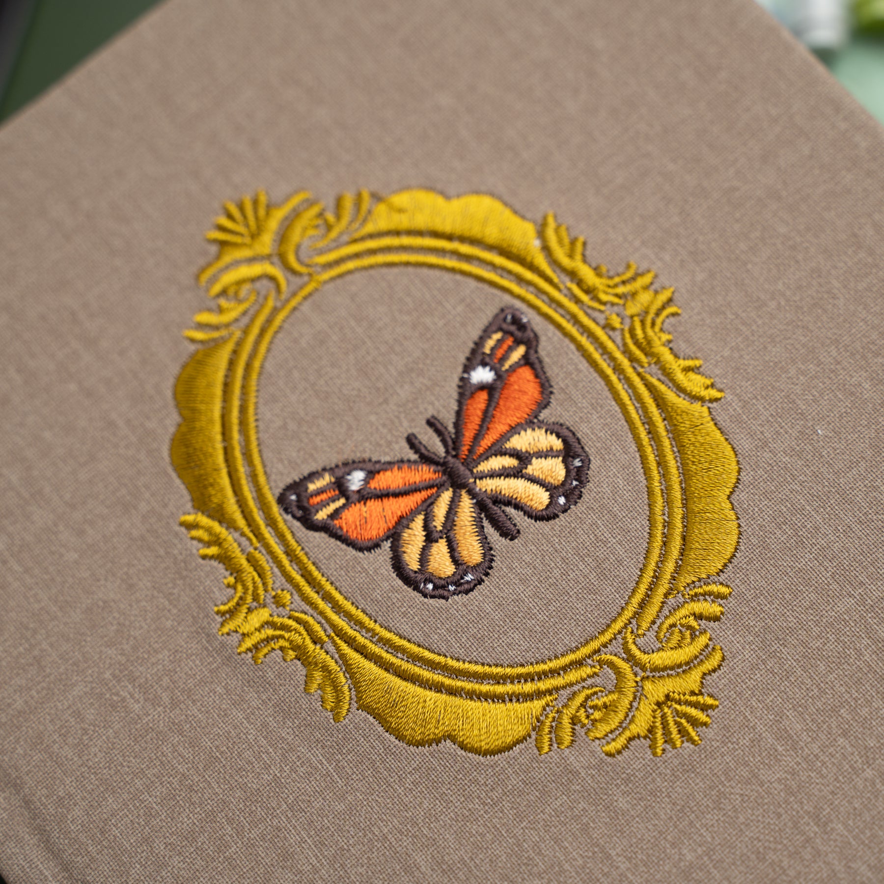 Embroidered butterfly design on a brown fabric background