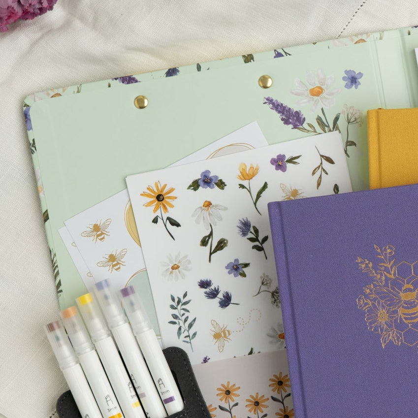 Notebooks and stationery items with floral designs on a light background