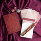 Stationery items including a red notebook, pen, and stationery set on a purple fabric background